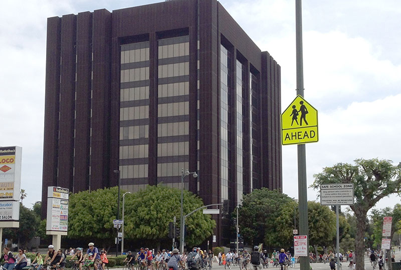 Contact Us at Eating Disorder Therapy LA [Image description: photo of the 10 story building at the corner of Highland and Wilshire with Los Angeles cyclists on the street during Cyclavia] 