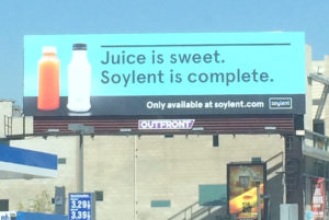 image description: billboard for Soylent that reads "Juice is sweet. Soylent is complete."
