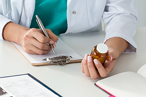 How to Communicate with Your Psychiatrist [image description: doctor holding bottle of medication and writing on clipboard]