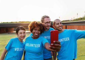 How to Be in And Celebrate Photos [image description: 4 people wearing volunteer shirts taking a selfie]