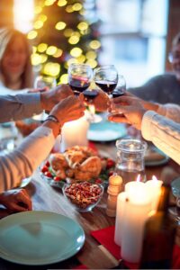 strategies for adults with Avoidant Restrictive Food Intake Disorder (ARFID) to navigate the challenges of the holiday season [Image description: a table set for the holidays with hands holding wine glasses clinking]